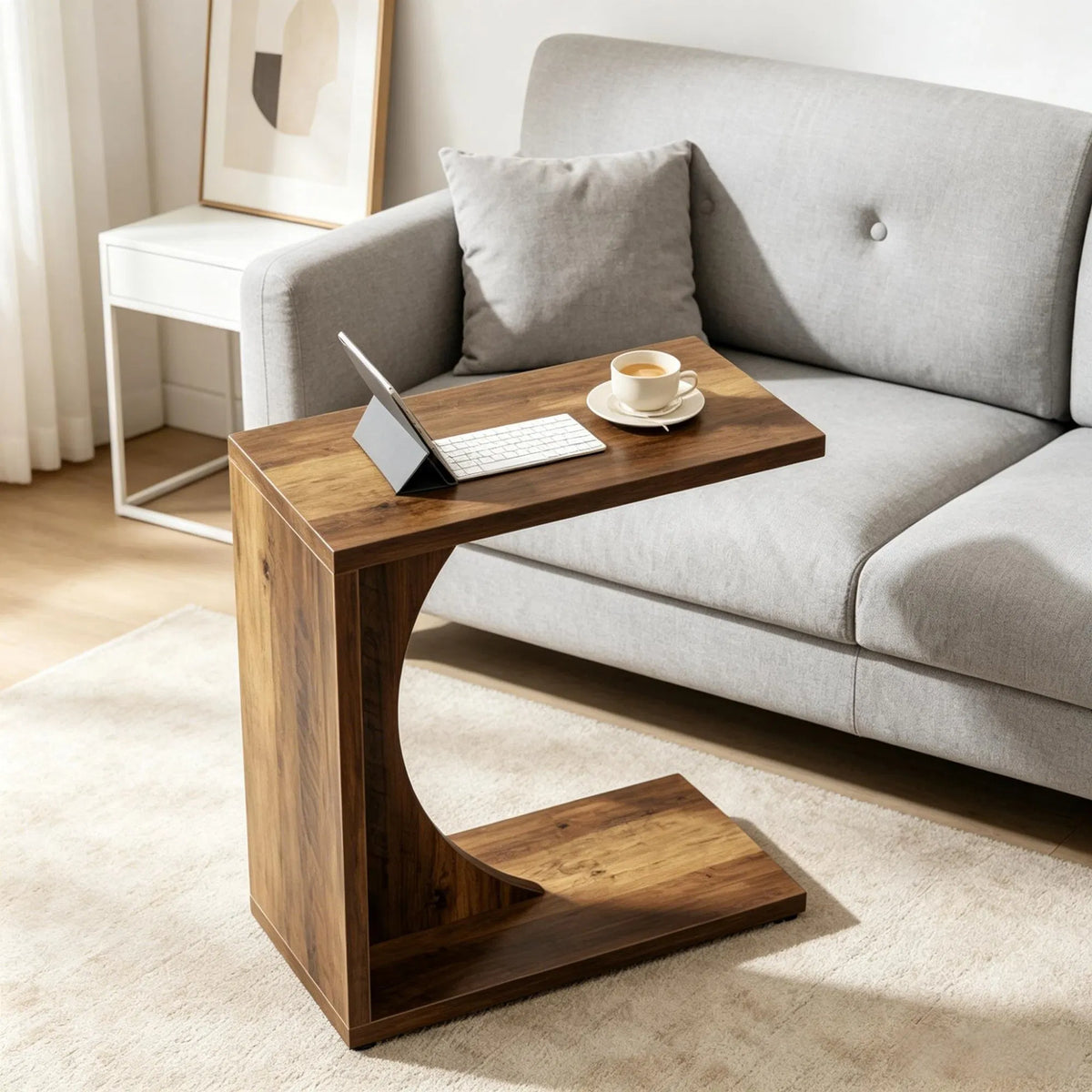C-shaped side table beside a sofa with a laptop and coffee
