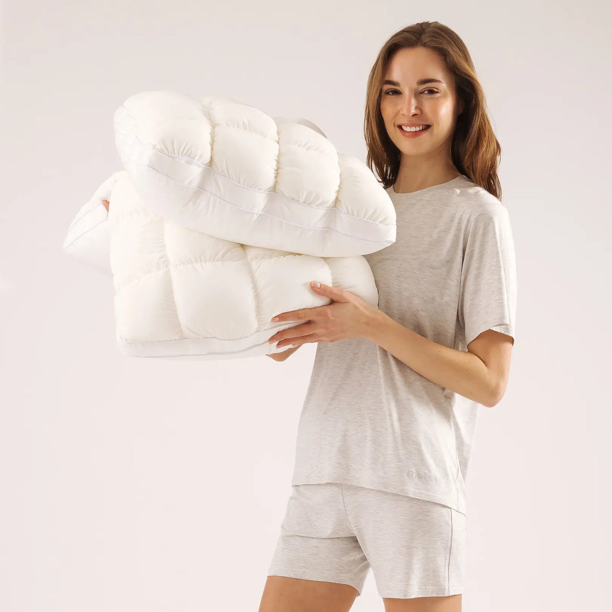 Woman holding two white quilted puff pillows
