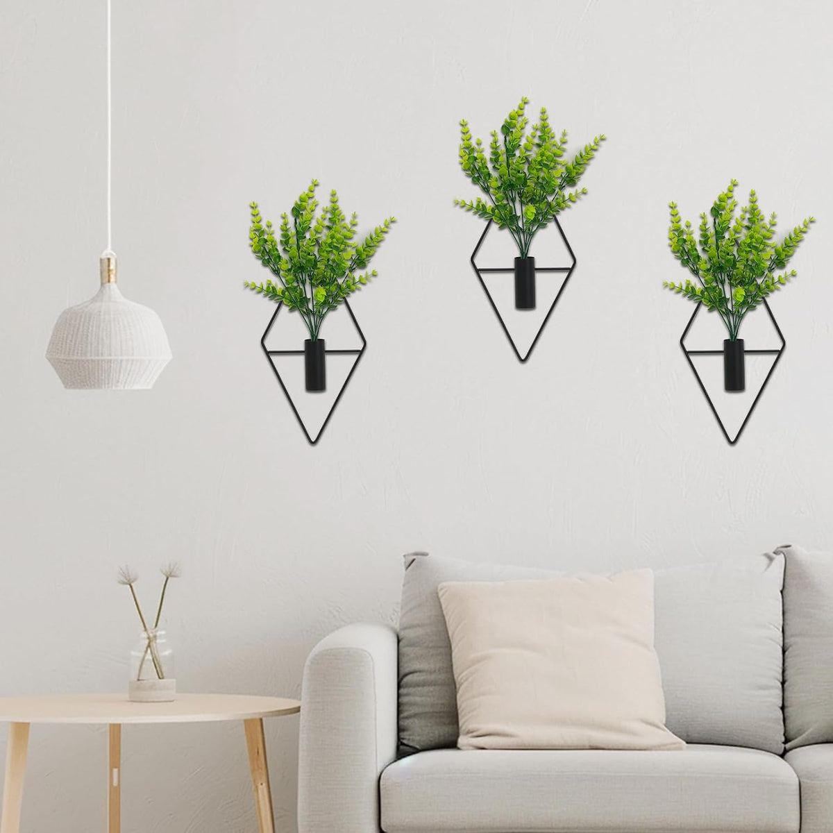 Three hanging eucalyptus planters on a white wall