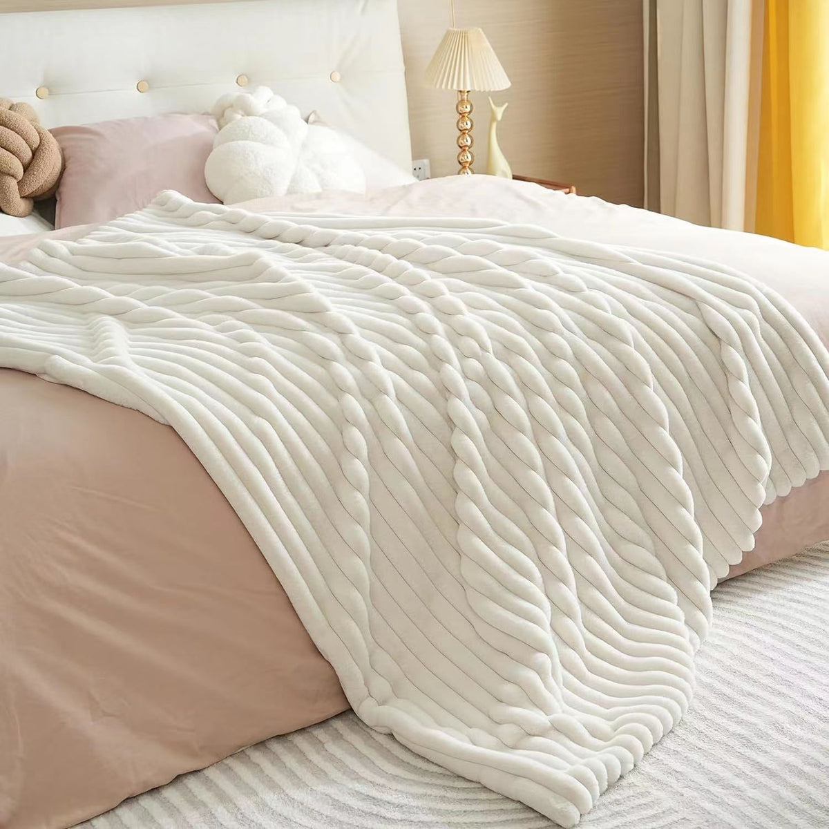 Ivory ribbed faux fur blanket draped over a bed